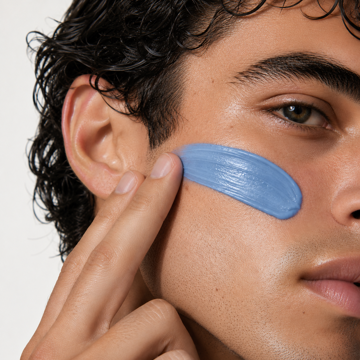 A man applying Vellume's periwinkle balm to his cheek