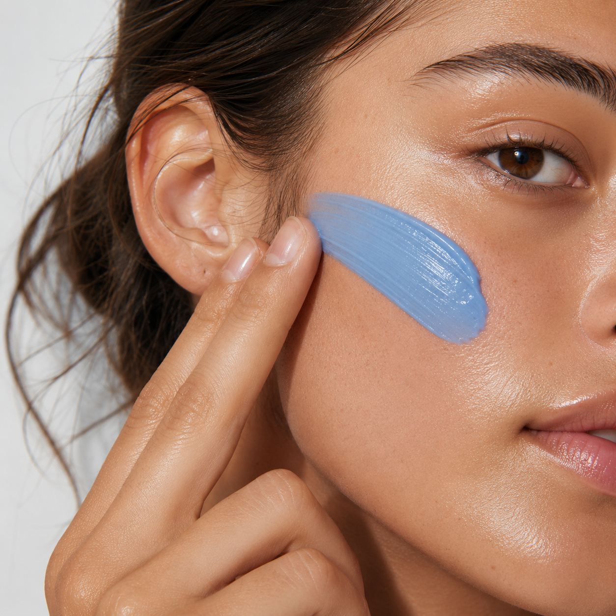 A woman applying Vellume's periwinkle balm to her cheek